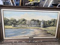 Full view of the framed painting showing castle and landscape by water.