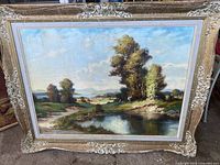 Full view of signed vintage landscape painting depicting trees by water and figures.