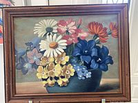 Full view of the framed vintage bouquet painting featuring various colorful flowers in blue vase on muted background.