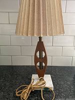 Full view of the teak lamp showing the fabric shade, teak body with cutouts, and marble base with cord.