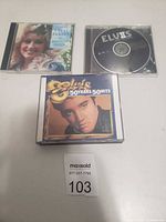 Three different music CDs in cases, Dolly Parton, Elvis Presley disc, and Elvis 50 Years 50 Hits CD.