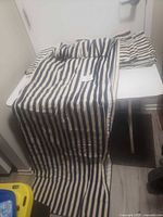 Photo showing one blue and white vertically striped curtain draped over a table, clearly showing length and width.