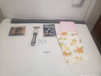 Photo showing lot contents including Tracy Chapman CD, paint scraper, two fabric pieces, small black packet, and small metal snowflake object
