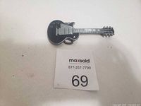 Front view of guitar-shaped belt buckle showing detailed guitar design in black and silver.