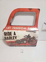 Front side of the metal tin sign shaped like a truck door with Harley Davidson graphics and text.
