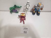 Four vintage kids action figures displayed on a white surface: Hulk, Iron Man, Star Wars Stormtrooper, and a futuristic soldier toy.