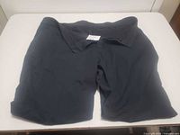 Men's blue dress pants folded and laid on a bed.