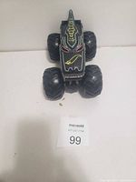 Front view of the black kids monster truck toy highlighting the monster eye and mouth design on the hood.