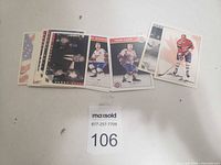 Photo showing a spread of 12 vintage hockey trading cards, featuring individual players and team photos in various historic uniforms.