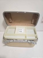 Open vintage makeup kit case showing the compartmentalized trays for organizing makeup items, fabric lining inside lid