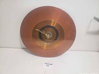 Front view of the vintage metal clock, showing its round face with concentric metal rings and gold-colored hands.