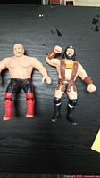 Two LJN wrestler figures displayed on black surface, showing front view with details on clothing and features.