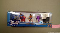 Photo of the original boxed set containing four DC Justice League figures: Batman, Superman, Wonder Woman, and The Joker showing the packaging and figures.