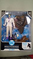 Front view of boxed DC Multiverse The Joker action figure with accessories and horse parts visible inside packaging.