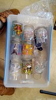 Top view of plastic bin containing 8 Disney collectible glasses with character prints