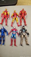 Photo of six Ironman-themed action figures arranged on a surface showing various suits and colors including red, gold, blue, and silver.