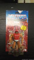 New sealed Masters of the Universe He-Man reproduction figure in red chest armor, packaged on red and blue card with Masters of the Universe branding.