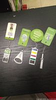 Photo of four metal bottle openers with keychains and Steam Whistle branded promotional cards on a black surface.