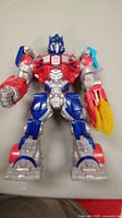 Photo of talking Optimus Prime action figure in red, blue and silver with yellow rocket launcher on left arm.