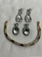 Photo of the bracelet and two pairs of drop earrings arranged on a fabric surface.