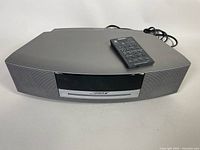 Front and top view of the BOSE Wave Music System with the remote control on top, showing overall condition and model design.