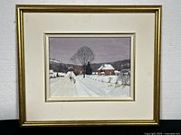 Framed watercolour painting depicting a winter landscape with a snow-covered road, leafless trees, a red brick house, and two figures walking along the road with a dog. Frame is gold with some nicks, and cream-colored matting has light stain.