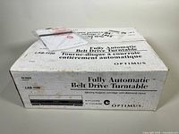 Original white packaging box labeled Optimus LAB-1100 Fully Automatic Belt Drive Turntable with text about features and brand.
