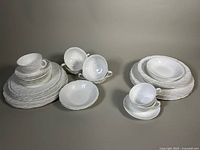 Overview of porcelain dishes from both Coalport and Wedgwood, showing assortment of plates, bowls, and teacup sets arranged on flat background.