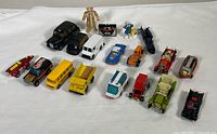 Wide view showing all 17 toy vehicles and figurines arranged on white background, multiple types, colors and styles.