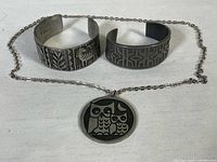 Photo of necklace chain with pendant and two cuff bangles together showing overall lot items and condition