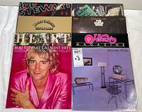 Photo shows all eight vinyl albums arranged upright and partially overlapping. The image highlights artwork featuring Rod Stewart, Heart, Elton John, and The Guess Who. Covers appear intact with minor wear.