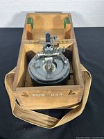 Top view of Type 02A compass seated in original wooden box with interior felt pads and canvas strap