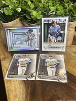 Four Bobby Witt Jr baseball cards displayed in plastic sleeves with plants in background