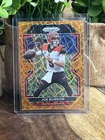 Front of Joe Burrow football card showing player in Bengals uniform with orange laser prismatic background.
