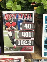 Photo of Tom Brady Next Level Stats football card showing performance metrics and player image in Buccaneers uniform.
