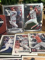 10 Shohei Ohtani baseball cards displayed in protective sleeves with action shots of batting and pitching for Angels and Dodgers, showing chrome and foil finishes.