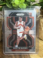 Front of Scottie Barnes rookie card showing player in Raptors uniform with Prizm reflective design and rookie card emblem.