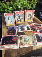 Photo showing an assortment of Star Wars trading cards spread on a table, featuring Luke Skywalker, Yoda, R2-D2, Darth Vader, and other Star Wars characters and scenes.