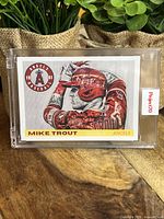 Front of the Mike Trout baseball card in protective case with artistic design and team logo.