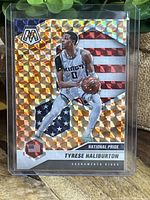 Front of the Tyrese Haliburton National Pride Mosaic Prizm basketball card showing the player in Sacramento Kings white uniform with an orange holographic mosaic pattern and American flag background.