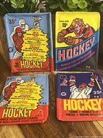 Five vintage O-Pee-Chee hockey card bubble gum wrappers in assorted colors and designs from the 1970s-1980s, showing front faces with prices and player illustrations.