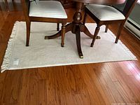 Top view showing area rug under a table with two chairs, highlighting size and fringed edges.