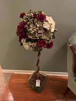 Full view of the artificial topiary tree showing twisted trunk, flower ball, and square base