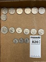Top view of assorted US half dollars arranged on cardboard showing various years including 1971 and smaller dimes in front.