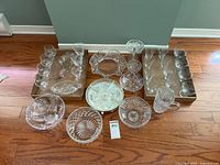 Overview of the cut glassware and crystal set showing bowls, serving dishes, stemware, and a pitcher arranged on a wood floor