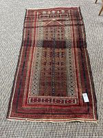 Full view of entire handwoven wool rug showing geometric design and overall condition on carpeted floor.