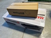Two cardboard boxes: unopened MAXhealth 4D accessory box atop opened MAXhealth 4D fitness board box