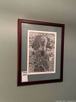 Framed charcoal drawing of seated figure with detailed outdoor background with a Masxold label 854 visible on bottom left corner of frame