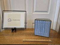 Boxed set of nine Little House books by Laura Ingalls Wilder, showing light blue slipcase and slight wear at box edges. Books arranged vertically inside box.