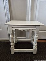 Front and side view of the wooden cream painted distressed accent table with turned legs and stretcher supports
